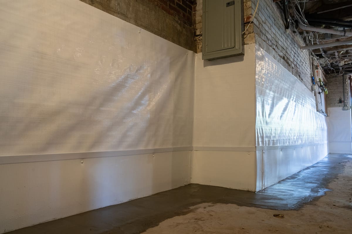 A specialist finishing concrete over a basement drainage installation