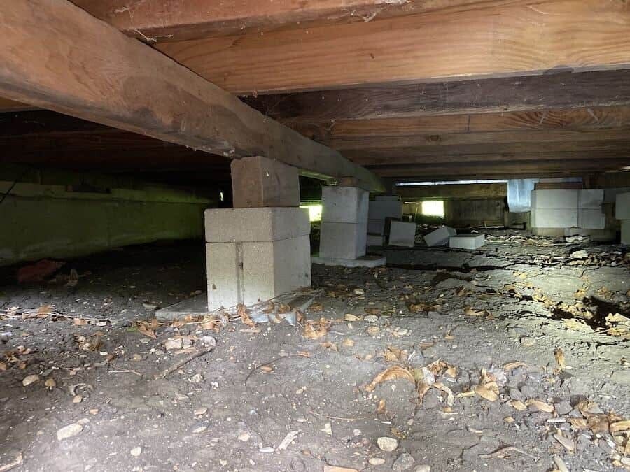 Wooden floor framing and masonry supports inside a crawl space