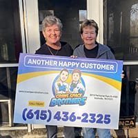Customers holding a Crawl Space Brothers customer sign