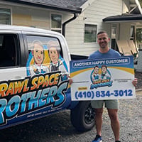 Customers holding a Crawl Space Brothers customer sign