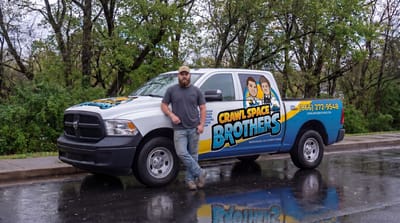 A Crawl Space Brothers team member beside the company truck.
