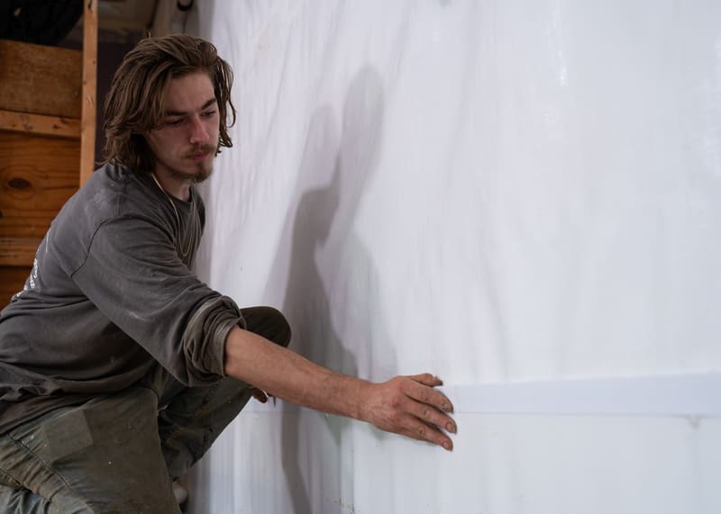 A specialist inspecting a basement wall