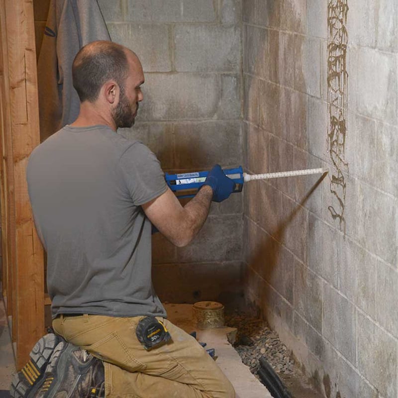 A specialist working alongside a basement foundation wall