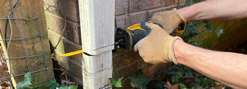 A worker preparing a gutter downspout for an underground drainage connection