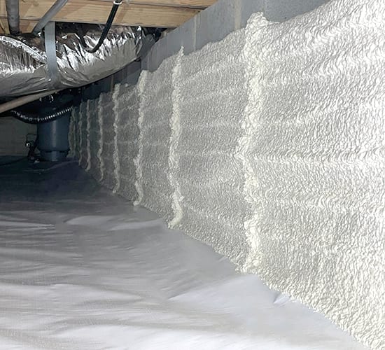 Spray foam insulation on foundation walls above a crawl space ground liner