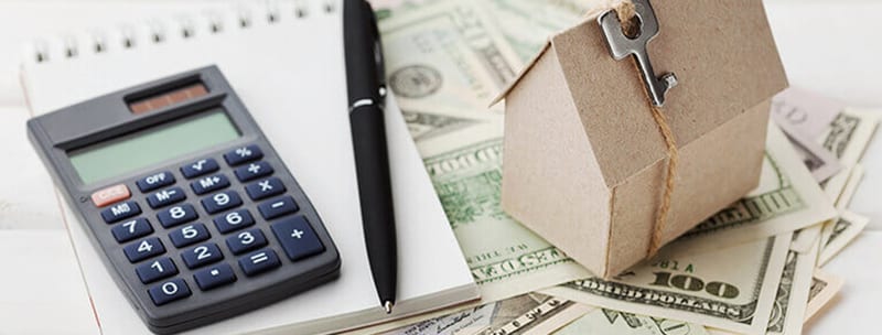 Calculator, cash and a small model house representing home energy costs