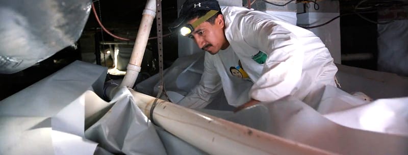 Crawl Space Brothers technician installing drainage and a liner in a crawl space