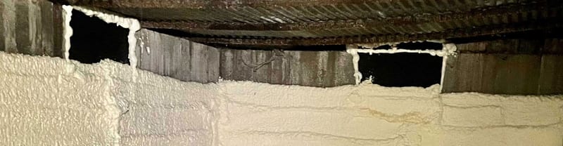 Closed vent openings with foam around their edges on a crawl space wall