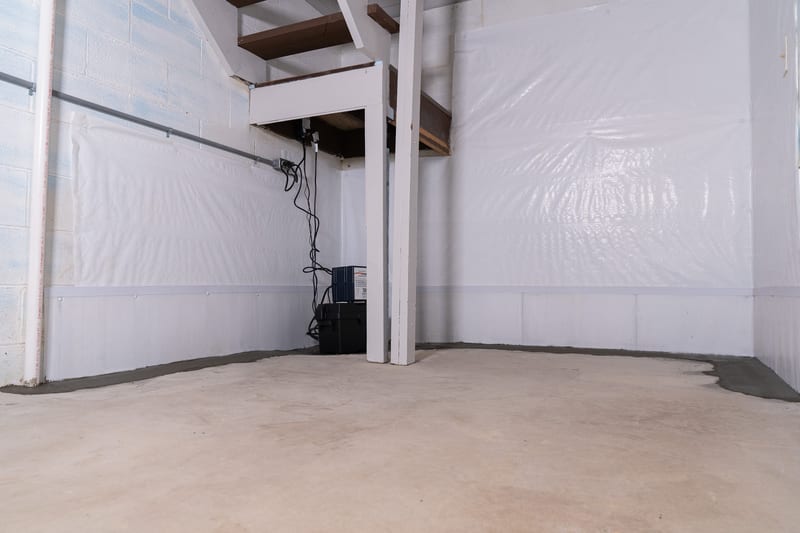 A specialist finishing concrete over a basement drainage installation
