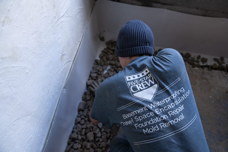 Concrete being finished above a basement drainage installation