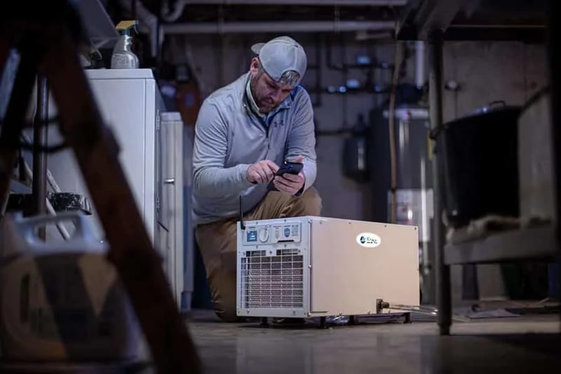 A technician checking a basement dehumidifier