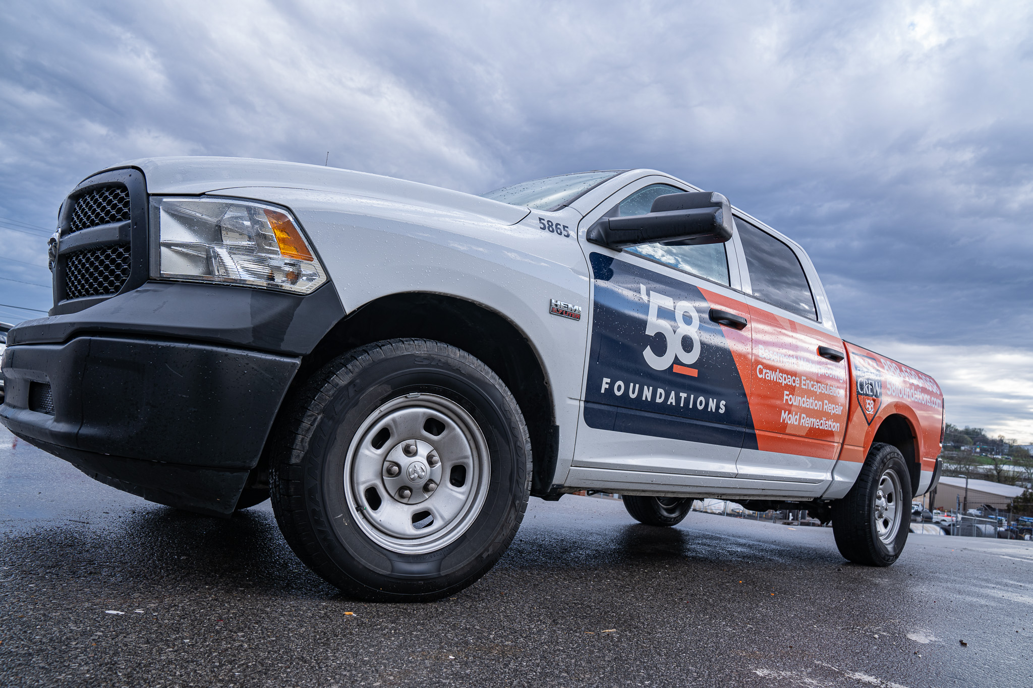 58 Foundations work truck parked on wet asphalt under a cloudy sky, advertising foundation repair services.